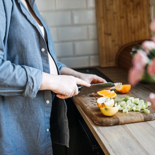 Fruits to avoid during pregnancy. Food allergy and pregnancy. Pregnant woman cutting fruits in the home kitchen.